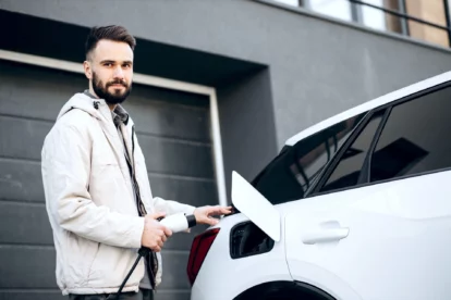 Man charging electric car by his house